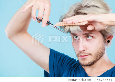 Man with scissors and comb creating new coiffure Man with scissors and comb creating new coiffure 136748655