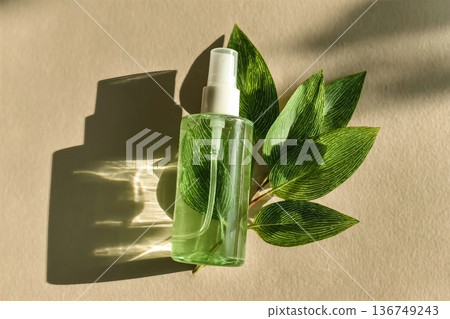 Transparent Cosmetic spray bottle and green leaf, natural light and shadow, dispenser with green liquid on beige. Natural Vegan skin care products, Eco-friendly Organic cosmetics concept, copyspace 136749243