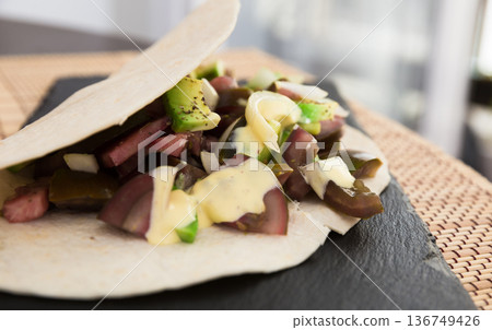 salad of black tomatoes, avocado and onions in Italian tortilla on black stone board salad of black tomatoes, avocado and onions in Italian tortilla on black stone board 136749426