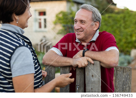 Elderly couple standing together near wooden fence in garden 136749433