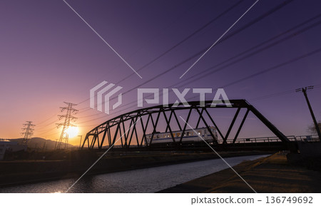 A train on the Chikuho Main Line crossing a railway bridge over the Homan River in the setting sun A train on the Chikuho Main Line crossing a railway bridge over the Homan River in the setting sun 136749692