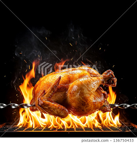 Grilled whole chicken on a spit over open flames, showcasing a delicious cooking process 136750433