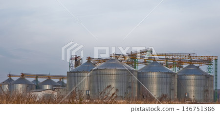 Industrial steel grain silos and conveyor systems in a rural landscape. Industrial steel grain silos and conveyor systems in a rural landscape. 136751386