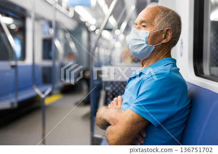 Portrait of male passenger riding in subway car in medical mask to prevent respiratory infection of Covid 19 Portrait of male passenger riding in subway car in medical mask to prevent respiratory infection of Covid 19 136751702