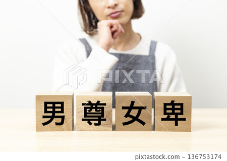 一名女子身穿圍裙,手持一塊寫著「男性沙文主義」字樣的木塊。 一名女子身穿圍裙,手持一塊寫著「男性沙文主義」字樣的木塊。 136753174