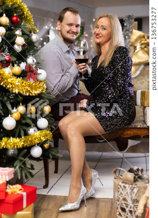Portrait of married couple in festive clothes with glass of red wine celebrating Christmas holiday 136753277
