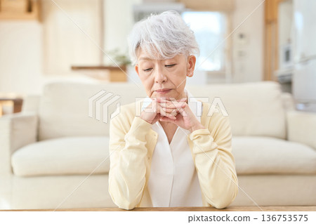 Asian senior woman resting her elbows in the living room Asian senior woman resting her elbows in the living room 136753575