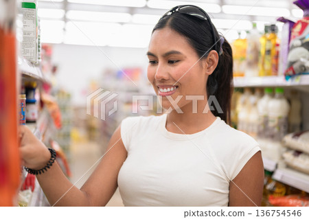 Young Woman Choosing Product from Supermarket Shelf 136754546