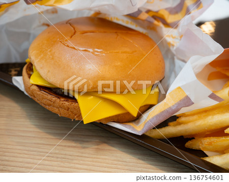 Close up shot of delicious double cheeseburger on the wooden table in fast food restaurant, unhealthy junk food meal and american dining concept. Close up shot of delicious double cheeseburger on the wooden table in fast food restaurant, unhealthy junk food meal and american dining concept. 136754601