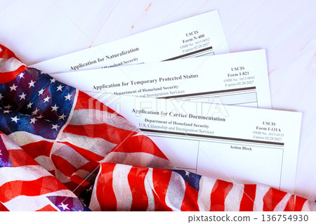 Application various forms for immigration are placed on citizenship immigration table next to an American flag. Application various forms for immigration are placed on citizenship immigration table next to an American flag. 136754930