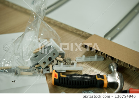 Close up of furniture hardware parts and metal rails on wooden panel, flat pack furniture assembly detail and DIY home improvement concept Close up of furniture hardware parts and metal rails on wooden panel, flat pack furniture assembly detail and DIY home improvement concept 136754946