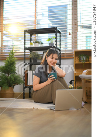 Joyful relaxed woman looking laptop with interest at home Joyful relaxed woman looking laptop with interest at home 136754947