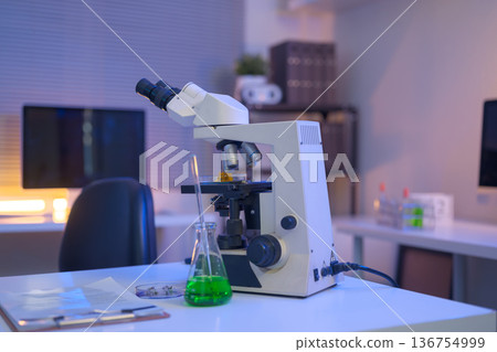 Laboratory workspace with microscope, green chemical solution, and research documents, representing modern scientific analysis and controlled experimentation. Laboratory workspace with microscope, green chemical solution, and research documents, representing modern scientific analysis and controlled experimentation. 136754999