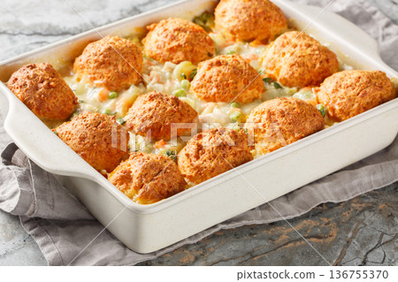 Chicken and biscuit casserole with added vegetables such as onions, carrots, green peas, celery with creamy sauce close-up in a baking dish horizontal Chicken and biscuit casserole with added vegetables such as onions, carrots, green peas, celery with creamy sauce close-up in a baking dish horizontal 136755370