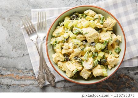Delicious curry chicken salad with crispy celery stalk, green onions and raisins dressed with yogurt close-up in a bowl. Horizontal top view 136755375