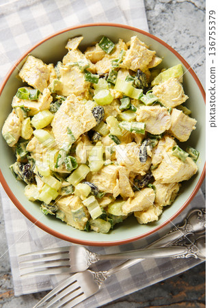 Curry salad with chicken, celery, raisins and green onions close-up in a bowl. Vertical top view 136755379