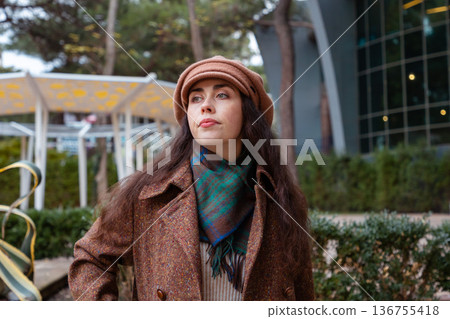 Young beautiful Caucasian woman in a coat enjoys an autumn walk in the quiet city, taking in the charm and beauty of a relaxed weekend moment outdoors 136755418