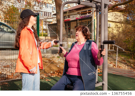 Mature woman trains with a coach in a park after medical treatment. Exercise helps restore endurance, balance, and wellbeing. 136755456