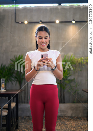 Young Woman Using Smartphone at Modern Outdoor Cafe 136755560