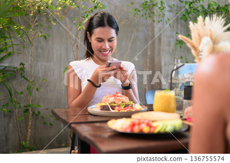Smiling Fitness Influencer Photographing Healthy Meal in Coffee Shop Restaurant Cafe Smiling Fitness Influencer Photographing Healthy Meal in Coffee Shop Restaurant Cafe 136755574
