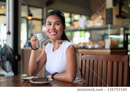 Smiling Woman Enjoying Espresso and Chocolate Cake in Coffee Shop Smiling Woman Enjoying Espresso and Chocolate Cake in Coffee Shop 136755584