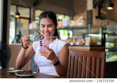 Happy Woman Enjoying Espresso and Chocolate Cake in Cafe Restaurant While Using Phone Happy Woman Enjoying Espresso and Chocolate Cake in Cafe Restaurant While Using Phone 136755586