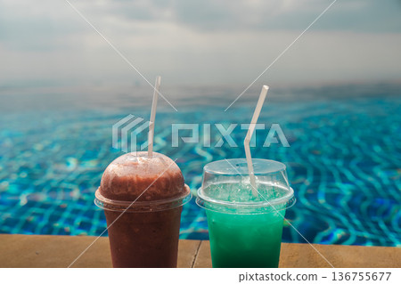 Two chilled drinks on infinity pool edge with blue water and soft sky creating tropical vacation refreshment scene and clean background for resort and travel concepts Two chilled drinks on infinity pool edge with blue water and soft sky creating tropical vacation refreshment scene and clean background for resort and travel concepts 136755677