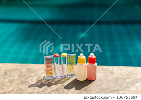 Pool water test kit with pH and chlorine scale and reagent bottles on pool edge, swimming pool maintenance and water quality control concept Pool water test kit with pH and chlorine scale and reagent bottles on pool edge, swimming pool maintenance and water quality control concept 136755694