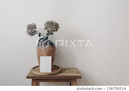 Minimalist Blank Greeting Card Invitation Mockup on Wooden Table Stool. Ceramic Vase with Dried Hydrangea Flowers. Neutral Rustic Home Decor Still Life, Copy Space. Modern Natural Interior Background 136756514