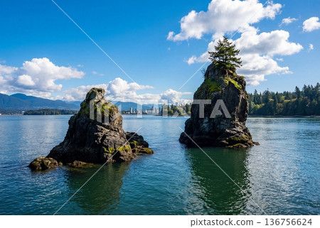 Siwash rock sea stack in stanley park with vancouver skyline and mountains under blue cloudy sky 136756624