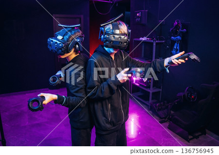 Doing hands gestures. Two young men in virtual reality glasses indoors Doing hands gestures. Two young men in virtual reality glasses indoors 136756945