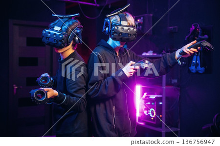 In the dark room. Two young men in virtual reality glasses indoors 136756947