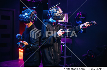 In the dark room. Two young men in virtual reality glasses indoors In the dark room. Two young men in virtual reality glasses indoors 136756948