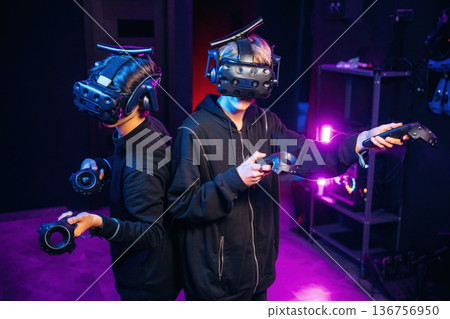 In the dark room. Two young men in virtual reality glasses indoors In the dark room. Two young men in virtual reality glasses indoors 136756950