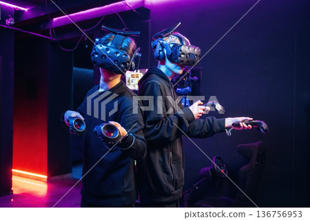 Eyewear on the heads and eyes. Two young men in virtual reality glasses indoors Eyewear on the heads and eyes. Two young men in virtual reality glasses indoors 136756953