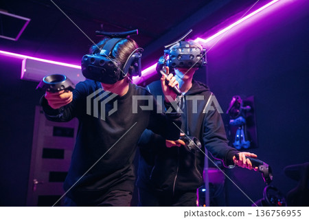 Eyewear on the heads and eyes. Two young men in virtual reality glasses indoors 136756955