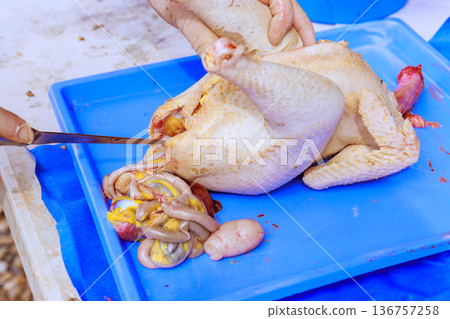 Cook cuts chicken to take out organs in kitchen where food is being prepared. Cook cuts chicken to take out organs in kitchen where food is being prepared. 136757258
