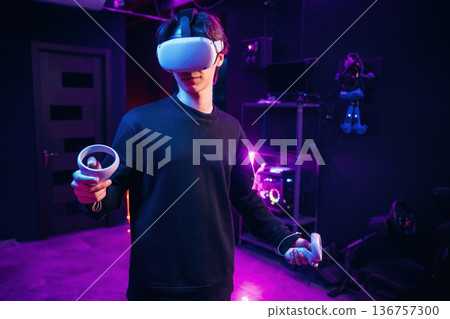Single player game. Young man is in virtual reality glasses indoors Single player game. Young man is in virtual reality glasses indoors 136757300