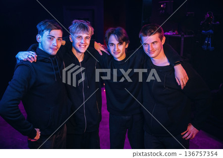 Embracing each other, posing. Gamers are standing in the dark room together Embracing each other, posing. Gamers are standing in the dark room together 136757354
