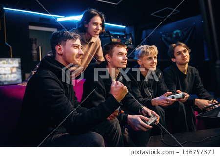 Victory, celebrating. Group of young gamers are indoors Victory, celebrating. Group of young gamers are indoors 136757371