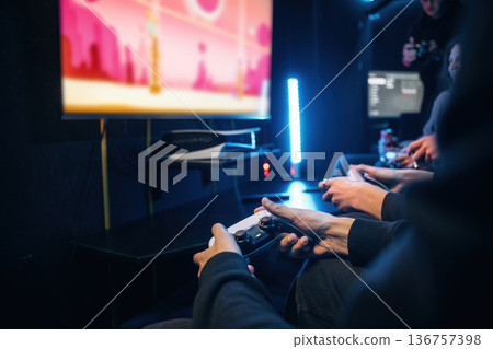 Holding controllers. Close up view of hands of gamers that playing game on console Holding controllers. Close up view of hands of gamers that playing game on console 136757398