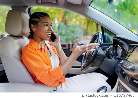 Young black woman talking on mobile phone while driving car, gesturing emotionally Young black woman talking on mobile phone while driving car, gesturing emotionally 136757465