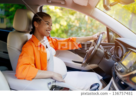 Young black pregnant woman smiling while driving car on sunny day 136757481