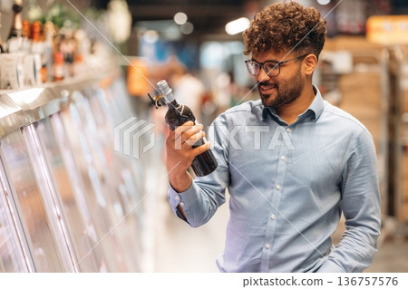 Bottle in hand. Man is in the grocery store Bottle in hand. Man is in the grocery store 136757576