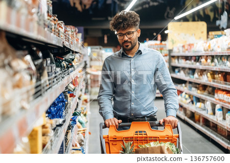 Front view. Man is in the grocery store Front view. Man is in the grocery store 136757600