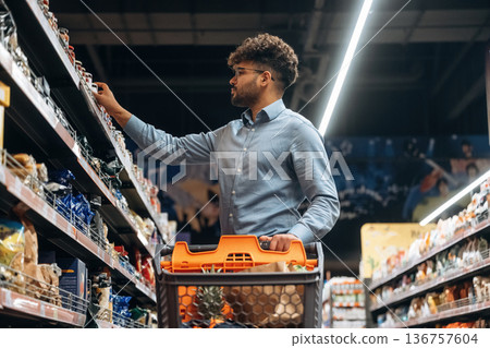 Taking the product. Man is in the grocery store 136757604