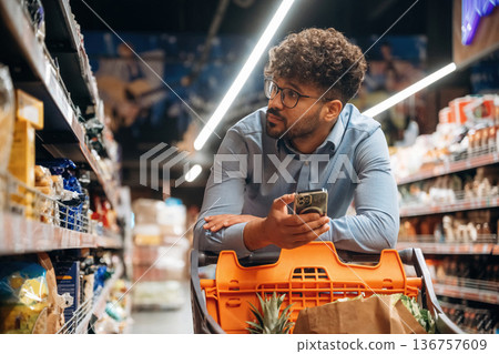 Customer is with phone. Man is in the grocery store 136757609
