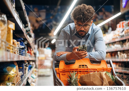 Customer is with phone. Man is in the grocery store 136757610