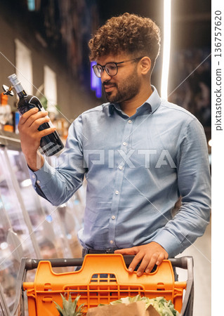 Bottle in hand. Man is in the grocery store Bottle in hand. Man is in the grocery store 136757620