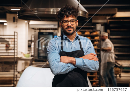 Bakery worker in apron is standing indoors 136757657
